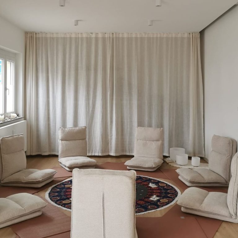 Junge Frau meditiert im Schneidersitz auf einem bunten Teppich mit Dekoration.