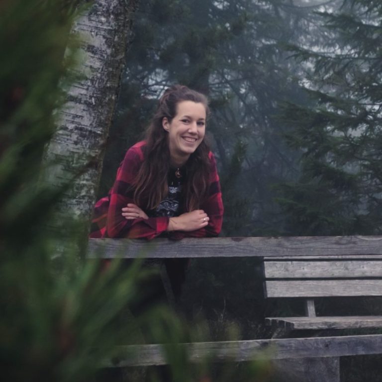 Vanessa Papp Junge Frau lehnt an einem Geländer auf einer Holzplattform im Wald. Vanessa Papp